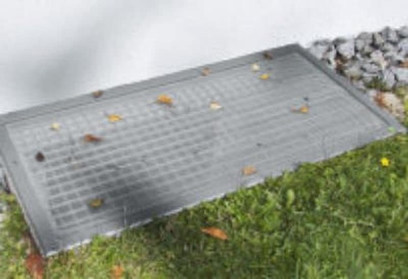 Abgedeckter Lichtschacht neben einer Rasenfläche